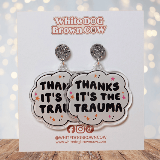 Clear acrylic dangle earrings with a speech bubble shape reading “Thanks it’s the trauma” with small star accents