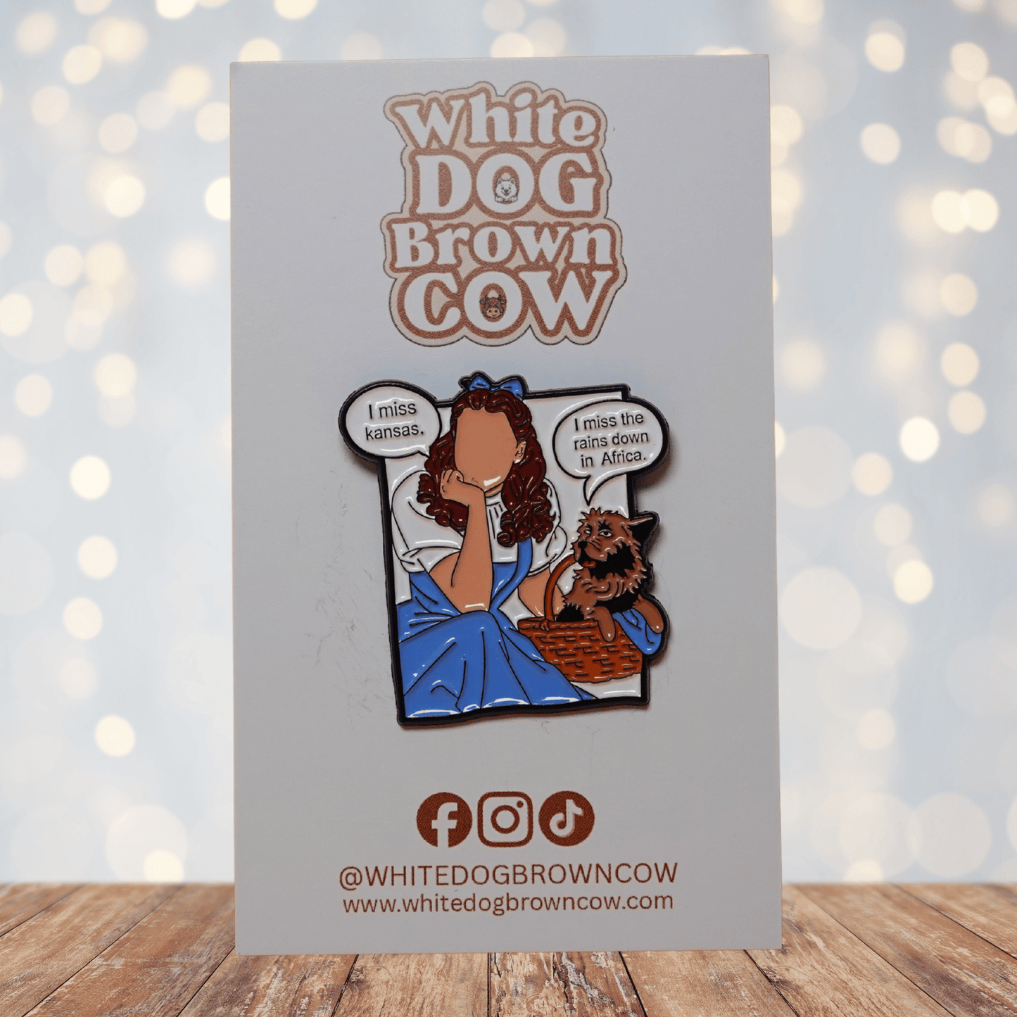 Enamel pin parody of Wizard of Oz with Dorothy and Toto saying “I miss Kansas” and “I miss the rains down in Africa,” funny pop culture mashup lapel pin.