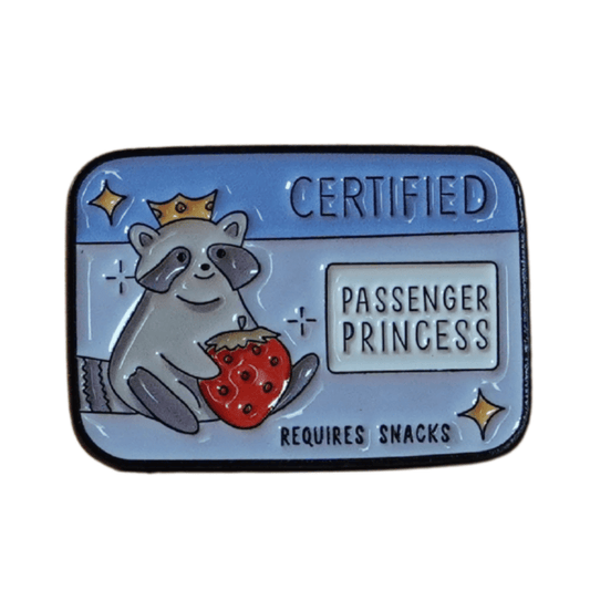 Raccoon enamel pin wearing a crown, holding a strawberry, with text “Certified Passenger Princess – Requires Snacks.”