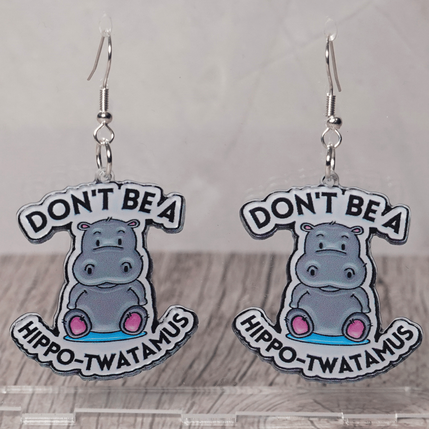 Novelty dangle earrings with a cute cartoon hippo and the phrase “Don’t be a hippo-twatamus”