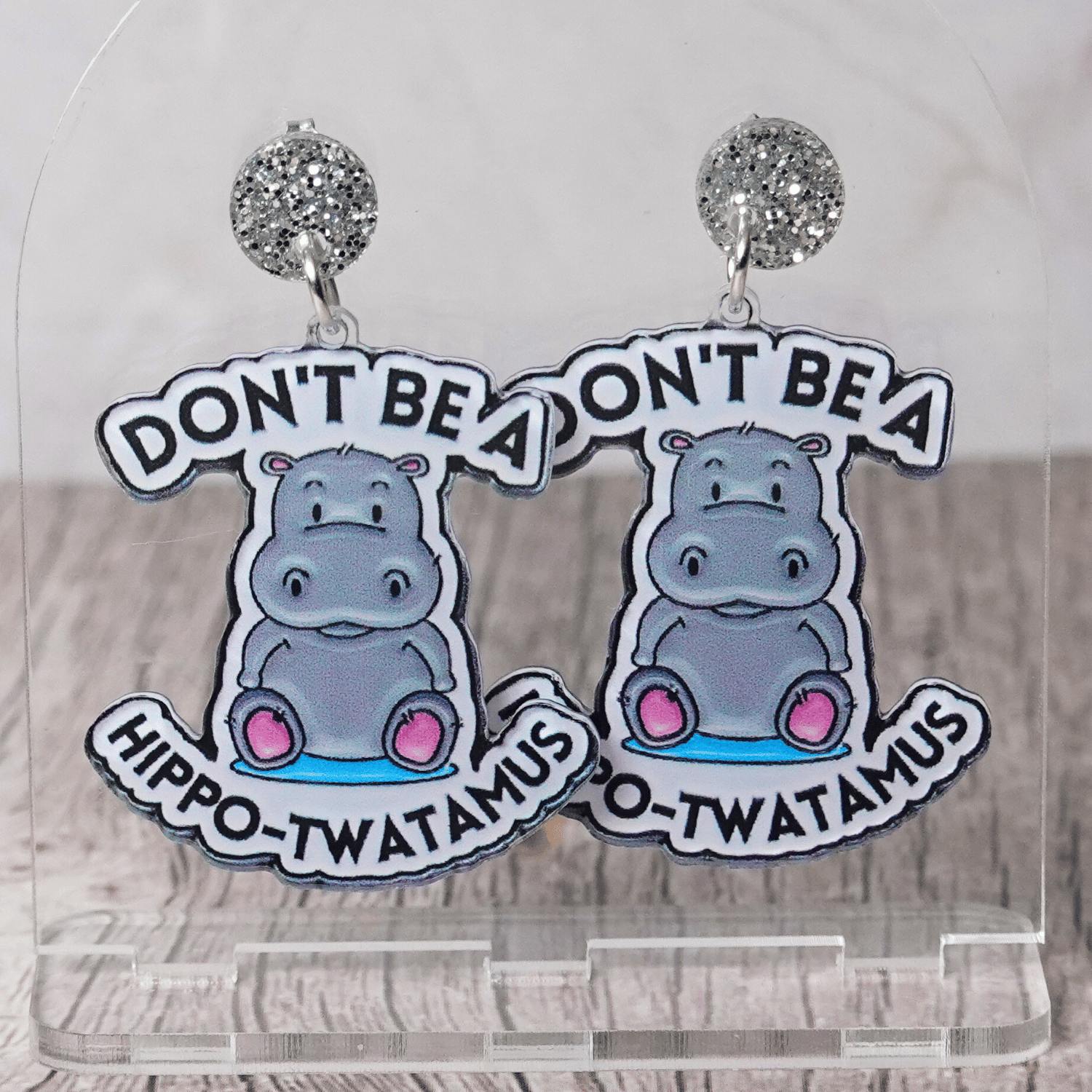 Novelty dangle earrings with a cute cartoon hippo and the phrase “Don’t be a hippo-twatamus”