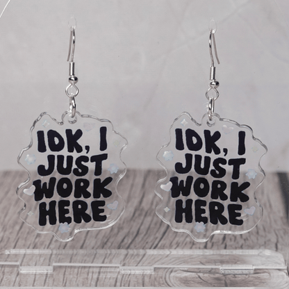 Clear acrylic dangle earrings with the phrase “IDK, I just work here” in bold black lettering