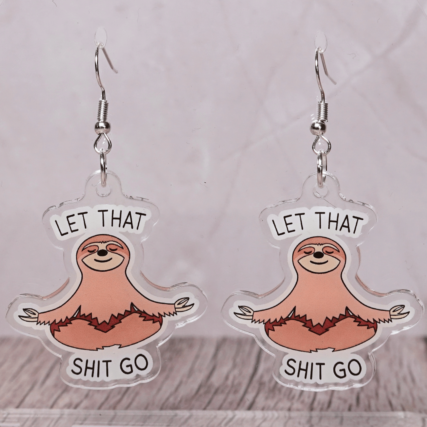 Cute sloth dangle earrings in meditation pose with text “let that shit go”