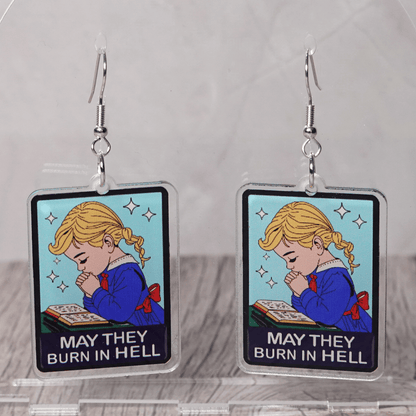 Clear acrylic dangle earrings with a vintage illustration of a praying girl and text reading “May they burn in hell”