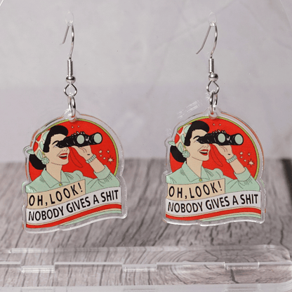 Retro style novelty dangle earrings showing a woman with binoculars and the phrase “Oh look nobody gives a sh*t”