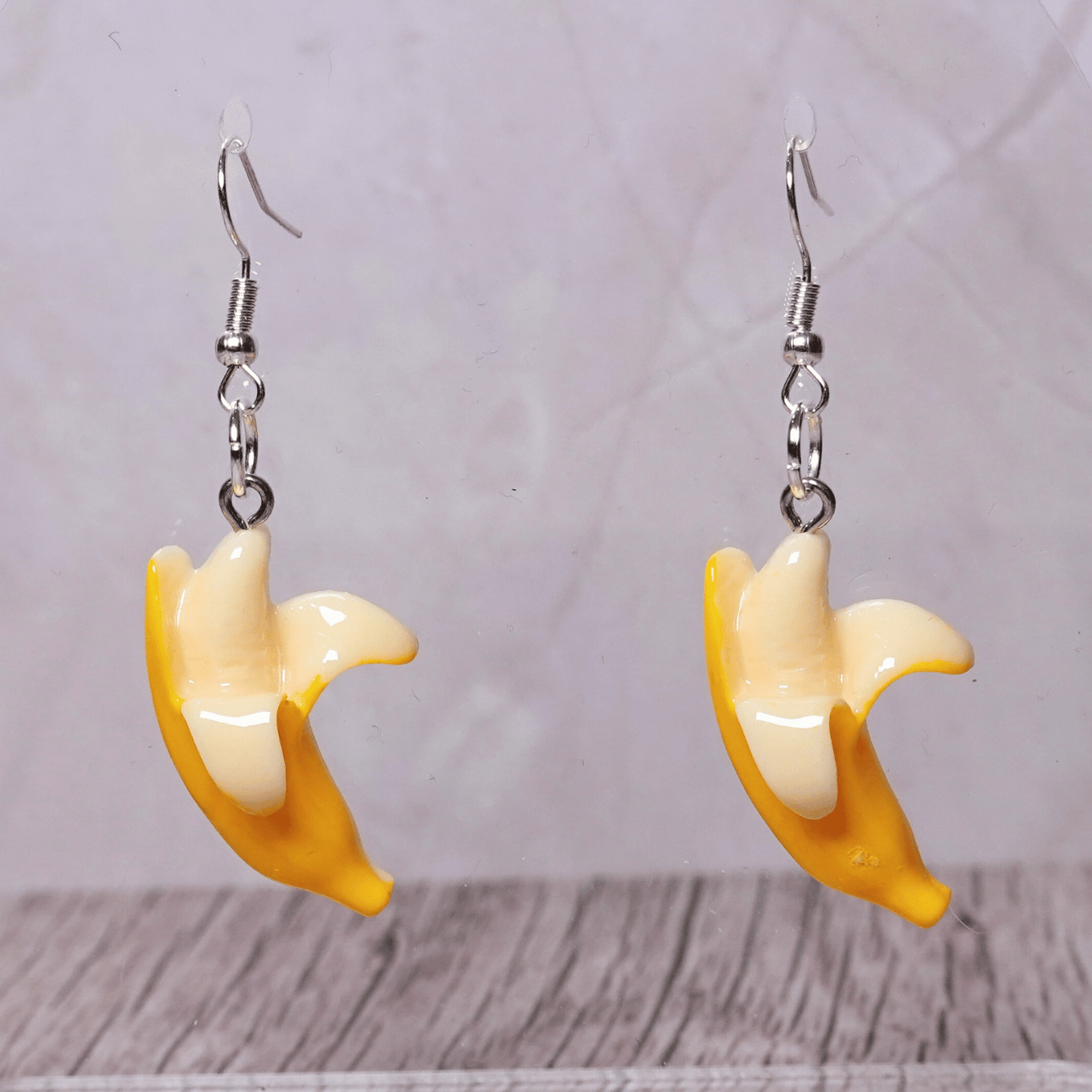 Cute dangle earrings shaped like partially peeled bananas with a realistic yellow and cream design.
