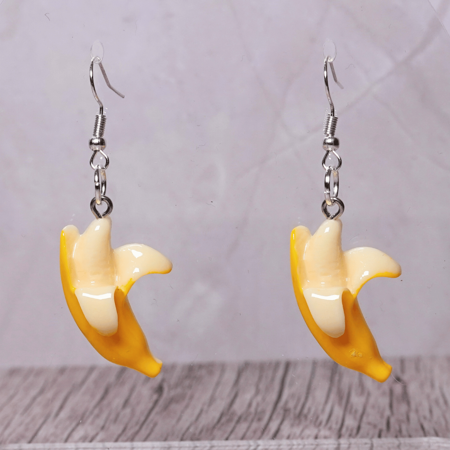 Cute dangle earrings shaped like partially peeled bananas with a realistic yellow and cream design.