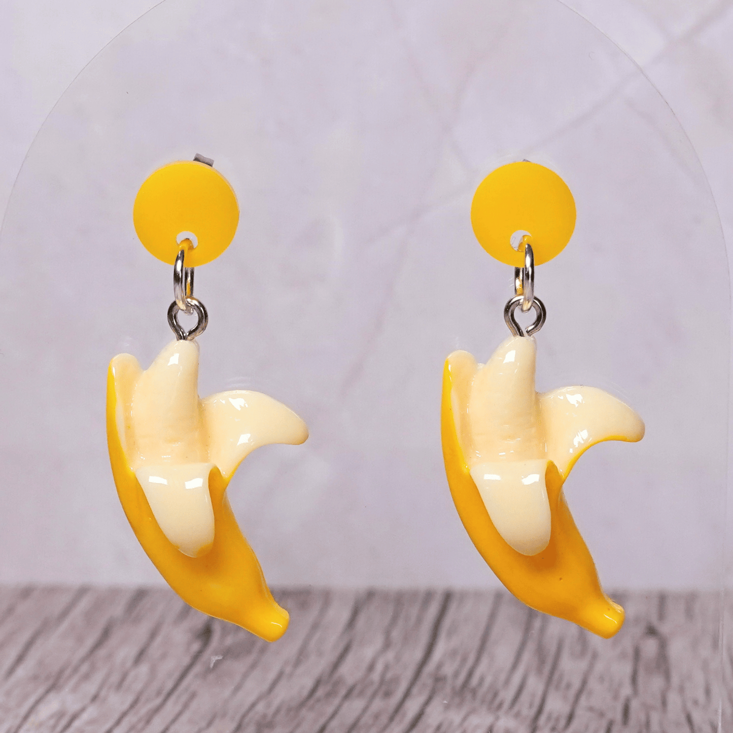 Cute dangle earrings shaped like partially peeled bananas with a realistic yellow and cream design.