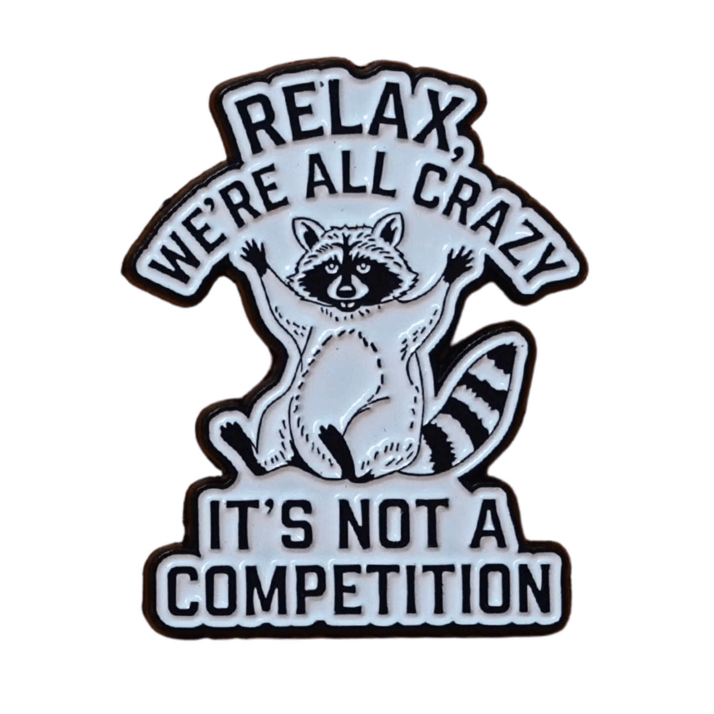 Black and white enamel pin with raccoon illustration and quote “Relax, We’re All Crazy, It’s Not a Competition,” funny sarcastic lapel pin.
