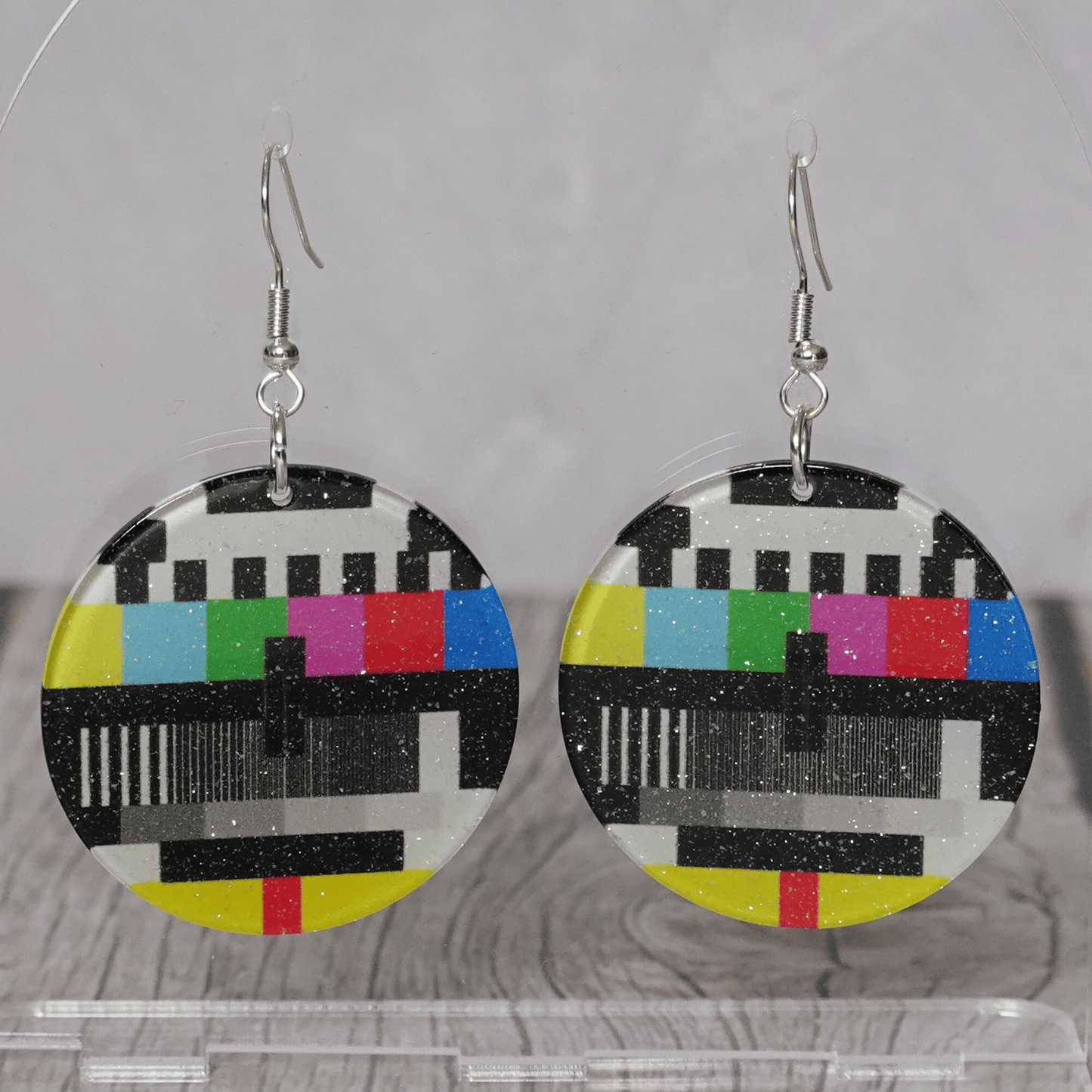 Round dangle earrings featuring a retro television test pattern with colorful bars and black and white graphics.