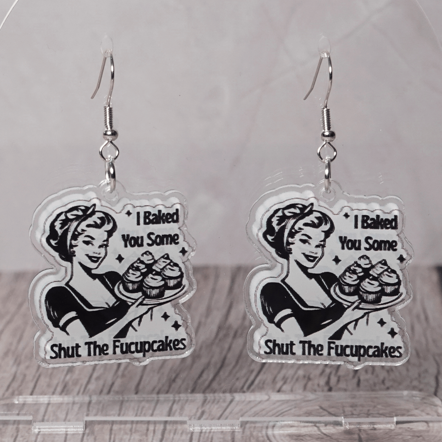 Retro style novelty dangle earrings with a vintage woman holding cupcakes and the phrase “I baked you some shut the fucupcakes”