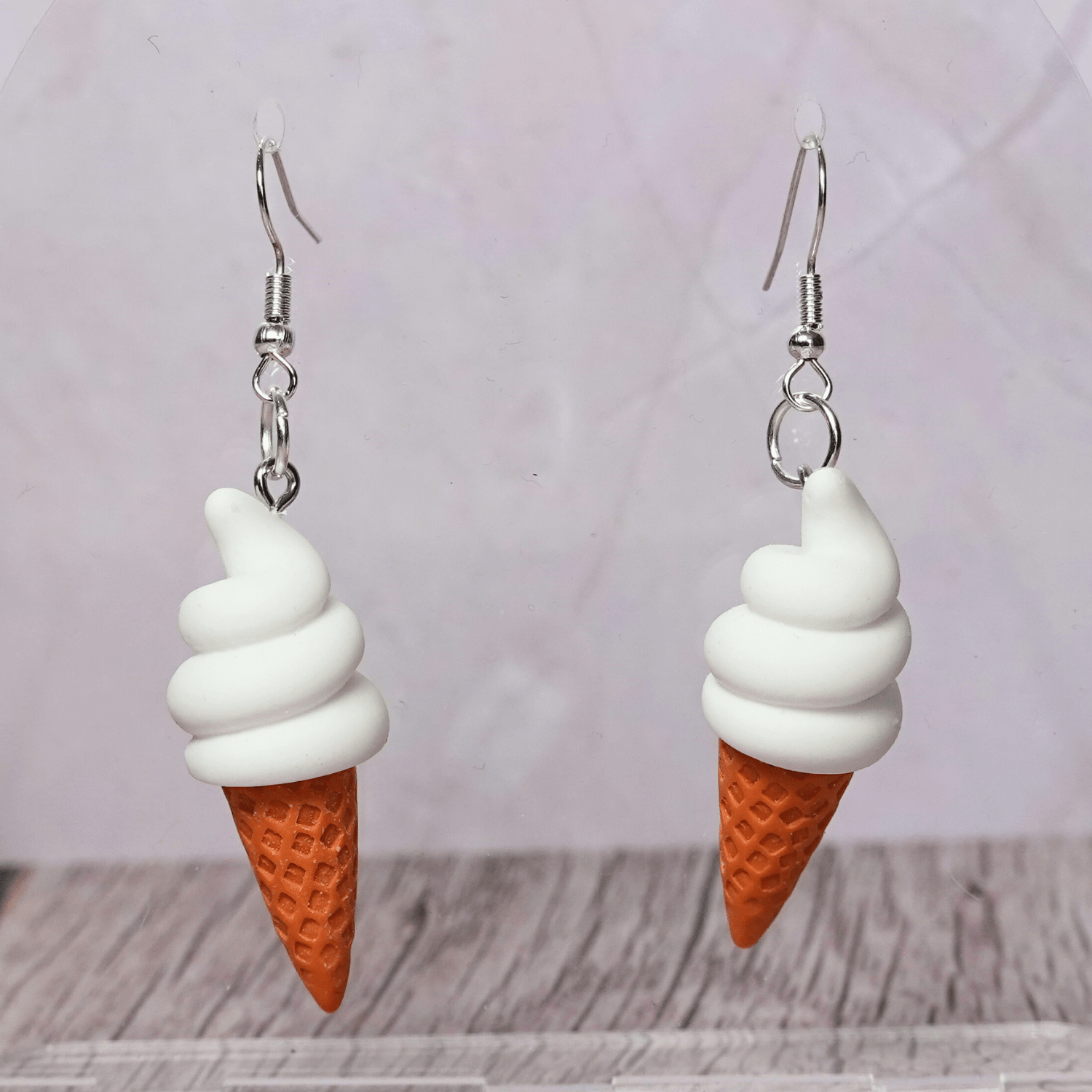 Cute dangle earrings shaped like soft serve vanilla ice cream in waffle cones.