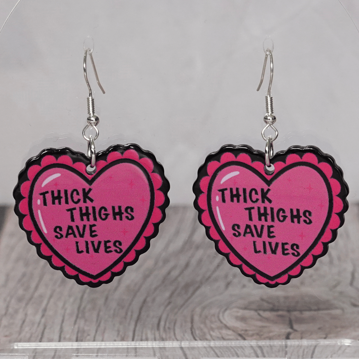 Pink heart dangle earrings with text “thick thighs save lives”