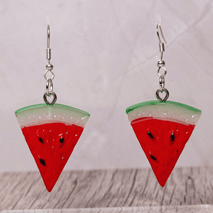 Watermelon slice dangle earrings shaped like red triangular watermelon pieces with green rind and black seed details on silver hooks.