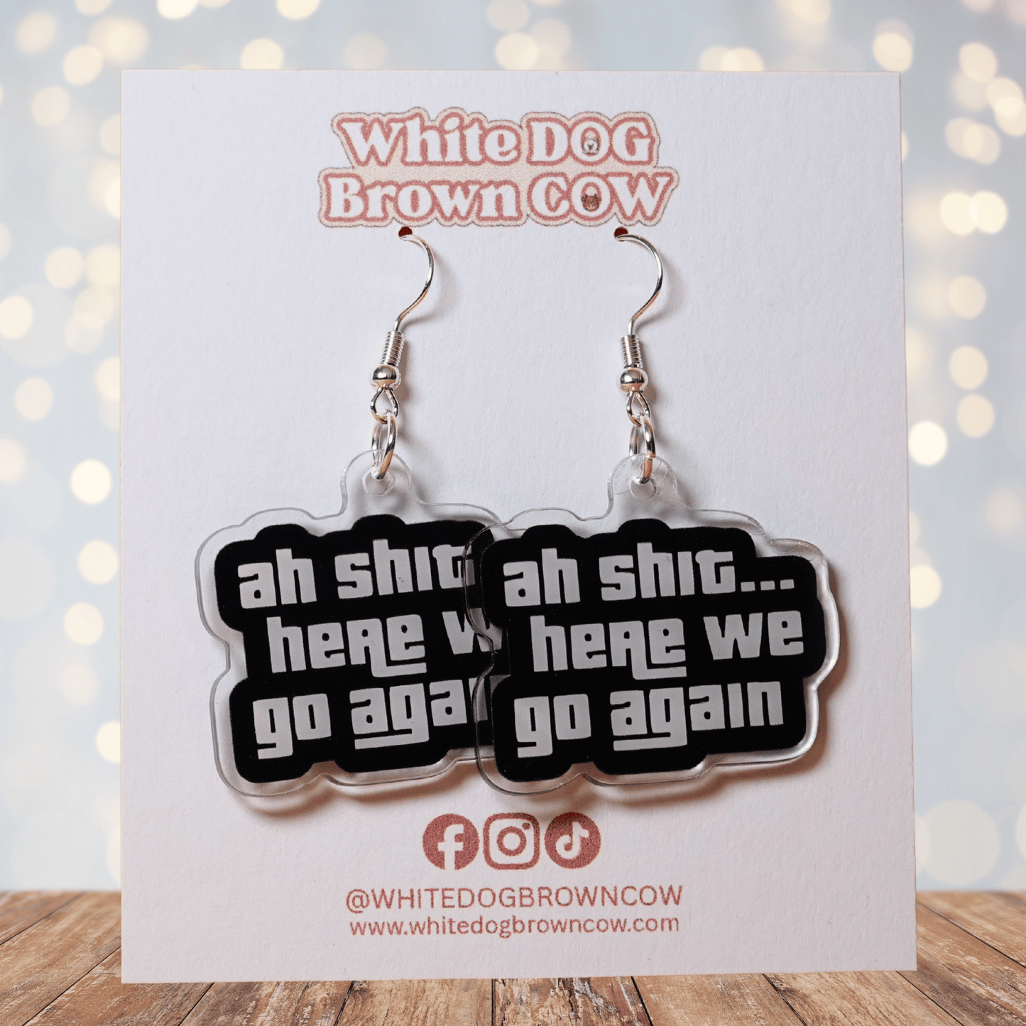 Black and white novelty earrings with text “ah shit here we go again”