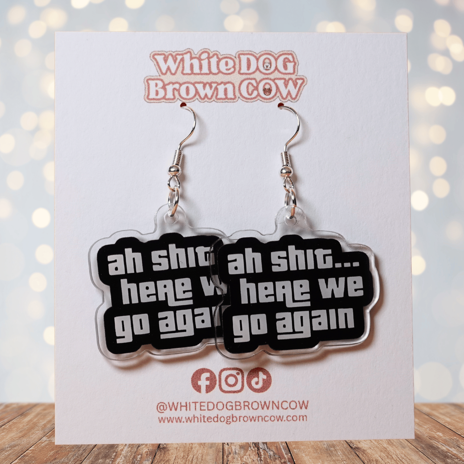 Black and white novelty earrings with text “ah shit here we go again”