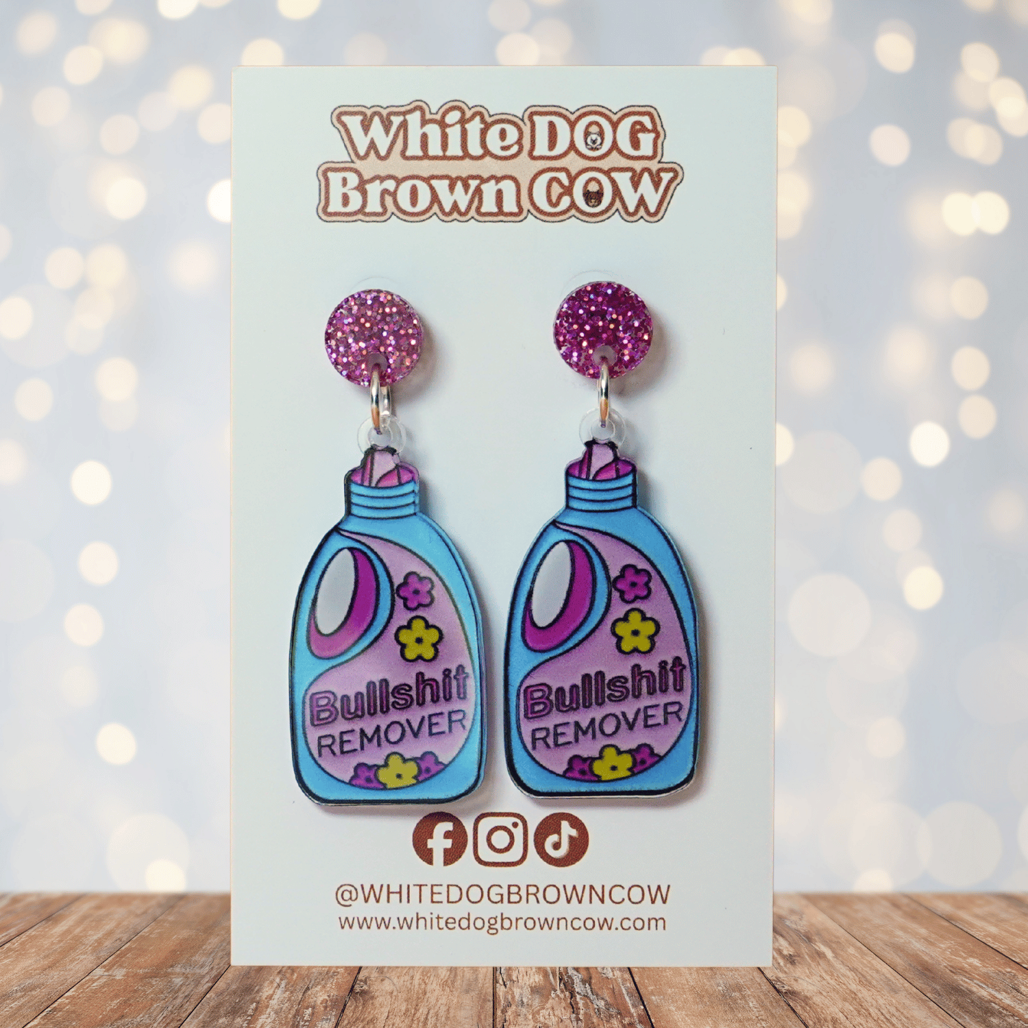 Colorful novelty dangle earrings shaped like a detergent bottle labeled “Bullsh*t remover”