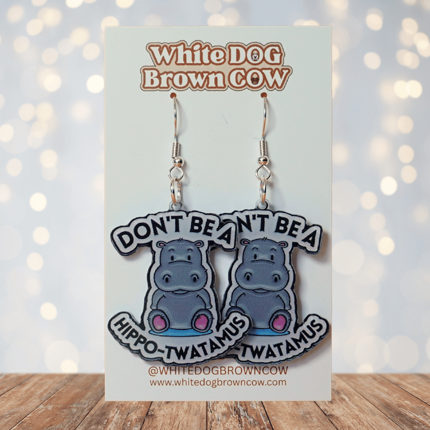 Novelty dangle earrings with a cute cartoon hippo and the phrase “Don’t be a hippo-twatamus”
