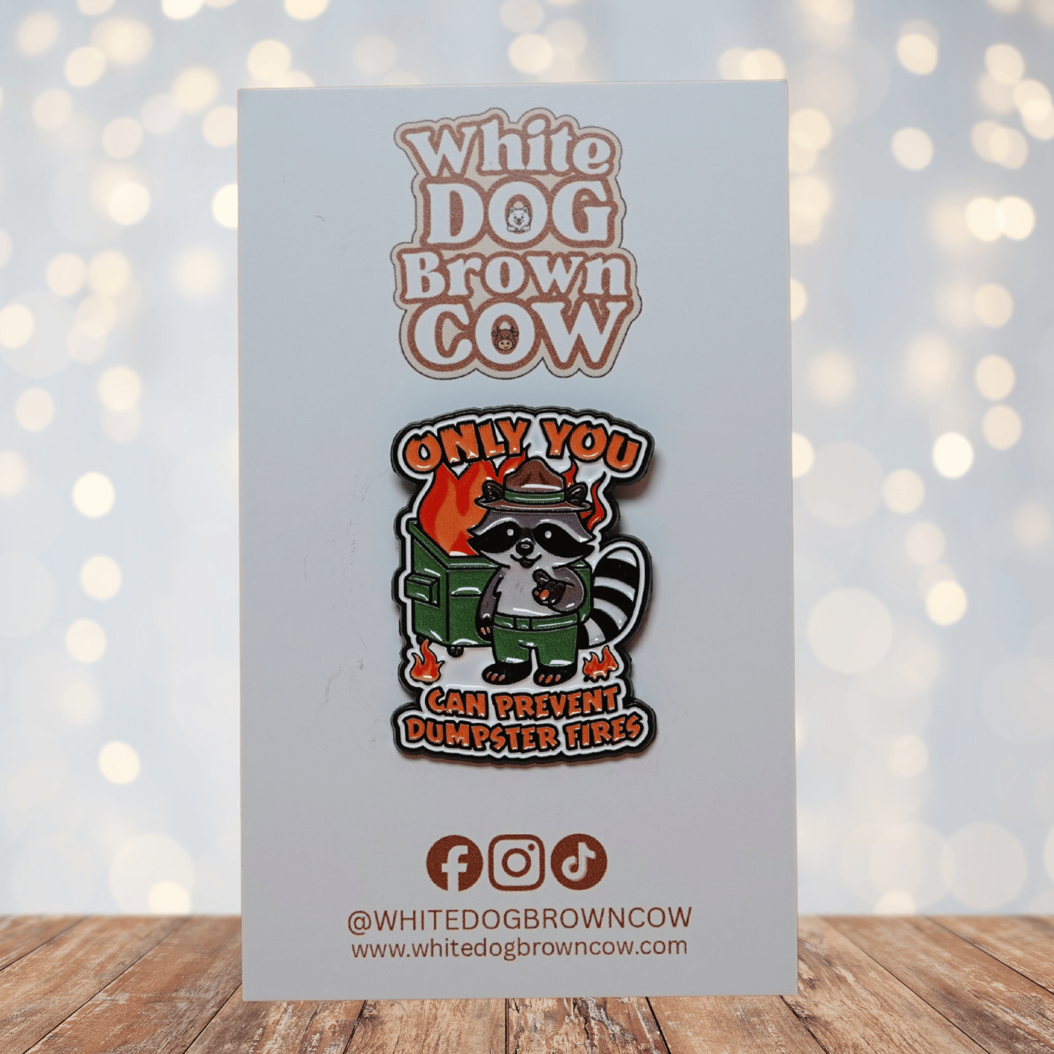 Funny raccoon enamel pin with burning dumpster design and quote “Only You Can Prevent Dumpster Fires,” sarcastic dark humor lapel pin.