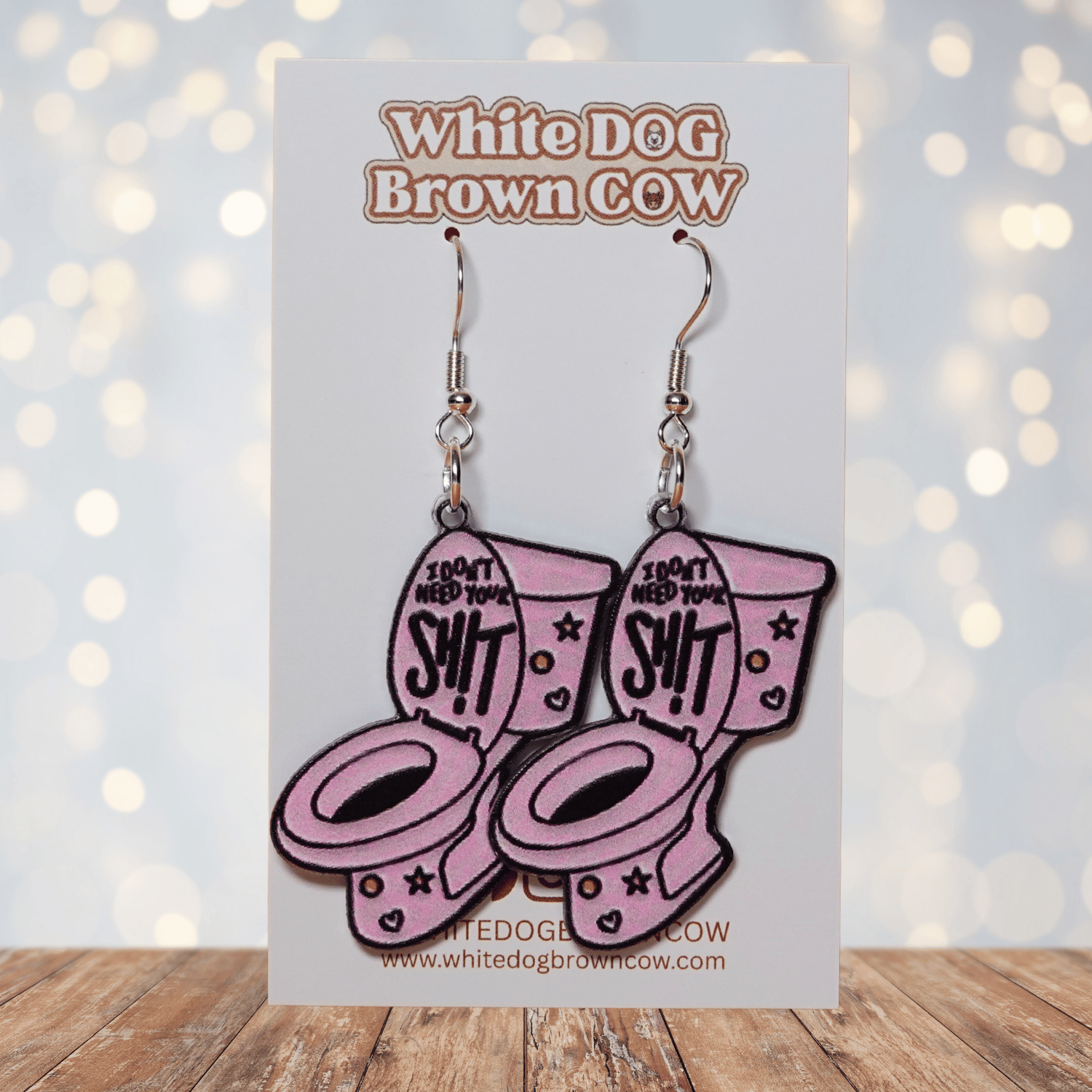 Pink novelty dangle earrings shaped like a toilet with text “I don’t need your sh*t”