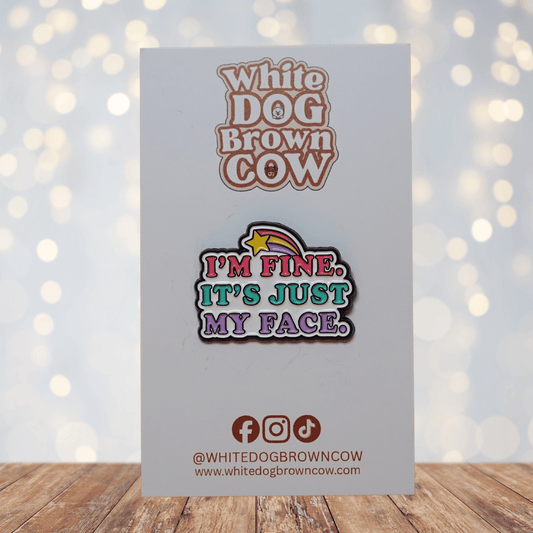Colorful enamel pin reading “I’m Fine, It’s Just My Face” with retro pink, teal and purple lettering and shooting star detail, funny sarcastic lapel pin.