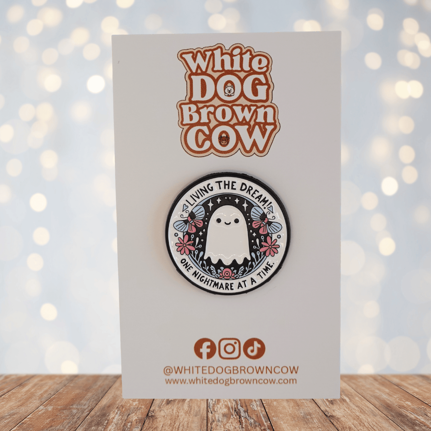 Cute ghost enamel pin with flowers and text “living the dream one nightmare at a time,” funny sarcastic spooky pin