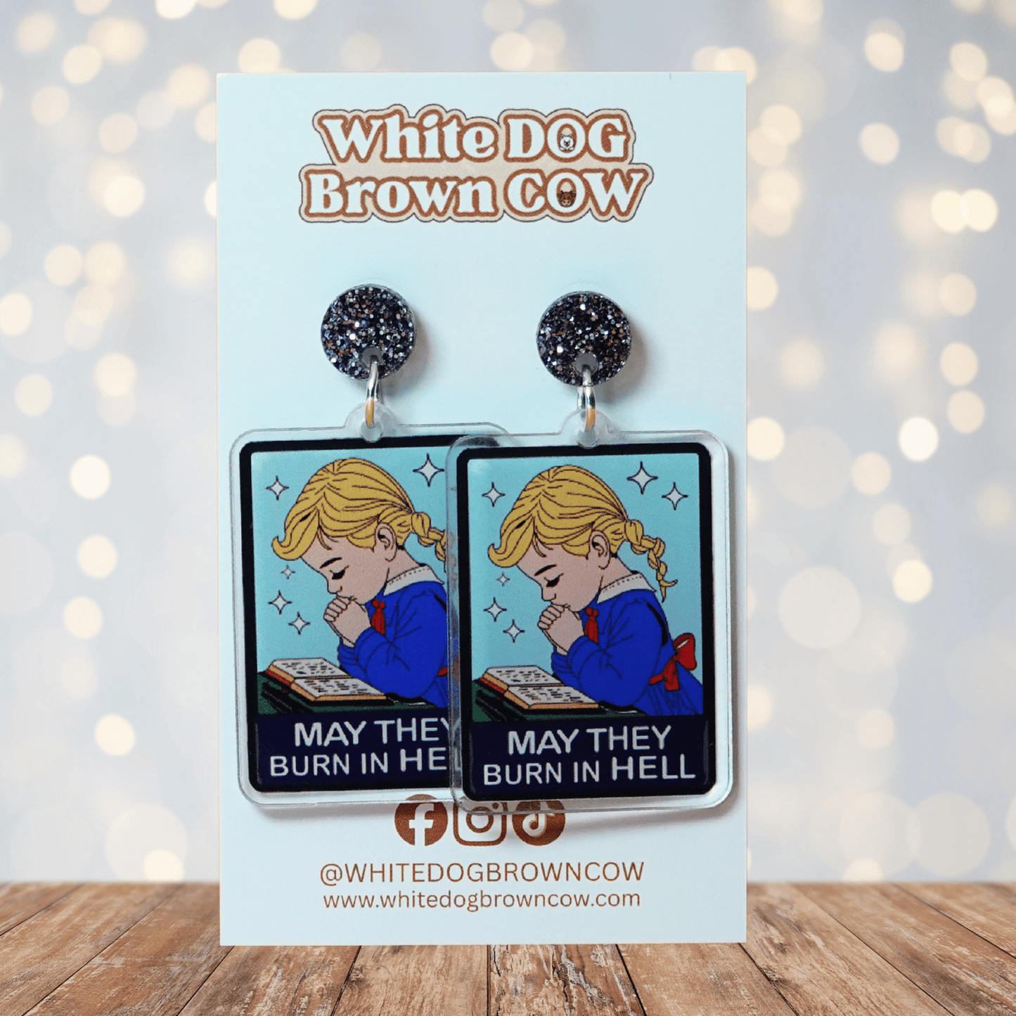 Clear acrylic dangle earrings with a vintage illustration of a praying girl and text reading “May they burn in hell”