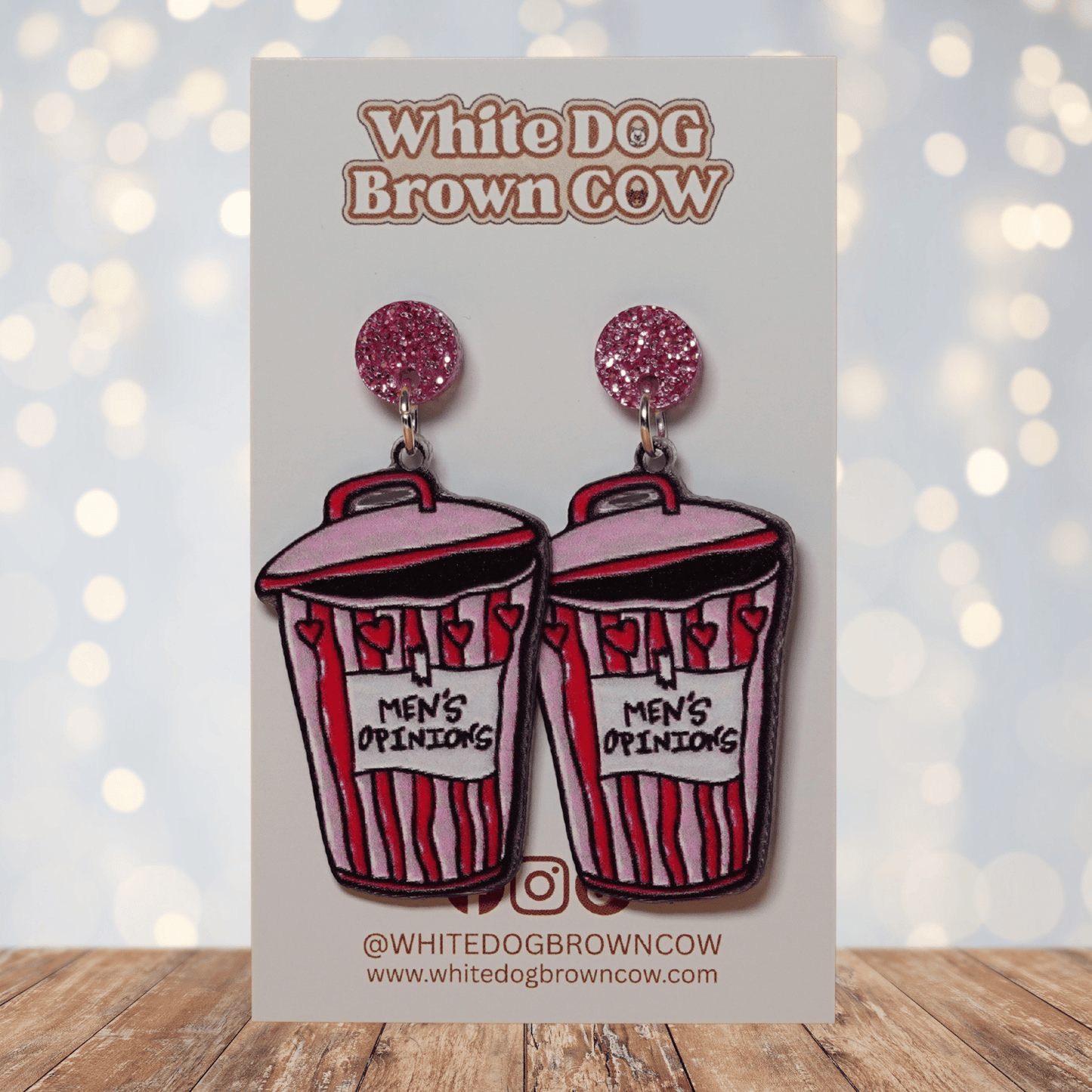 Acrylic dangle earrings shaped like a pink and red trash can labeled “Men’s Opinions”