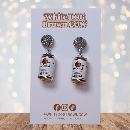 Novelty dangle earrings shaped like mini white rum cans with a printed label design and silver glitter studs.