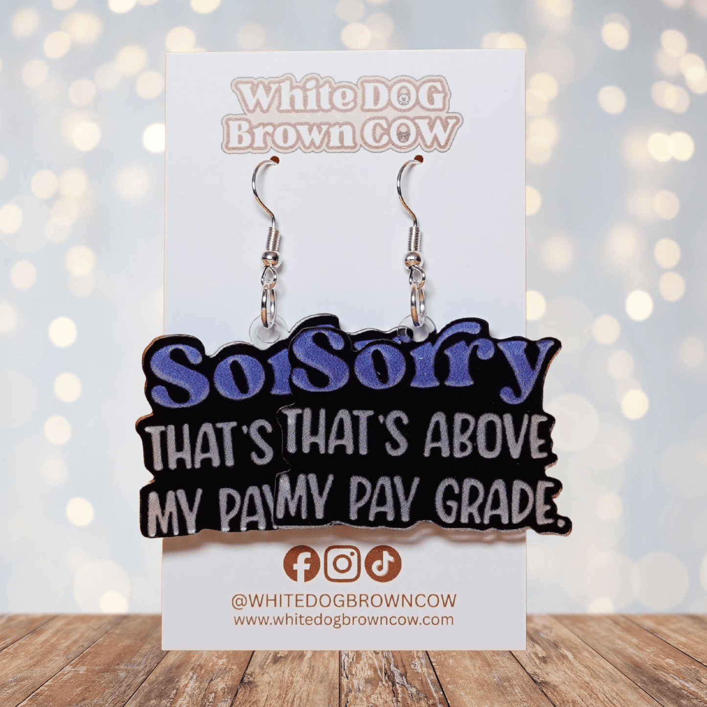 Black novelty dangle earrings with text “sorry that’s above my pay grade”