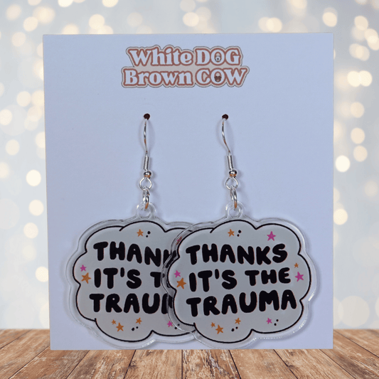 Clear acrylic dangle earrings with a speech bubble shape reading “Thanks it’s the trauma” with small star accents