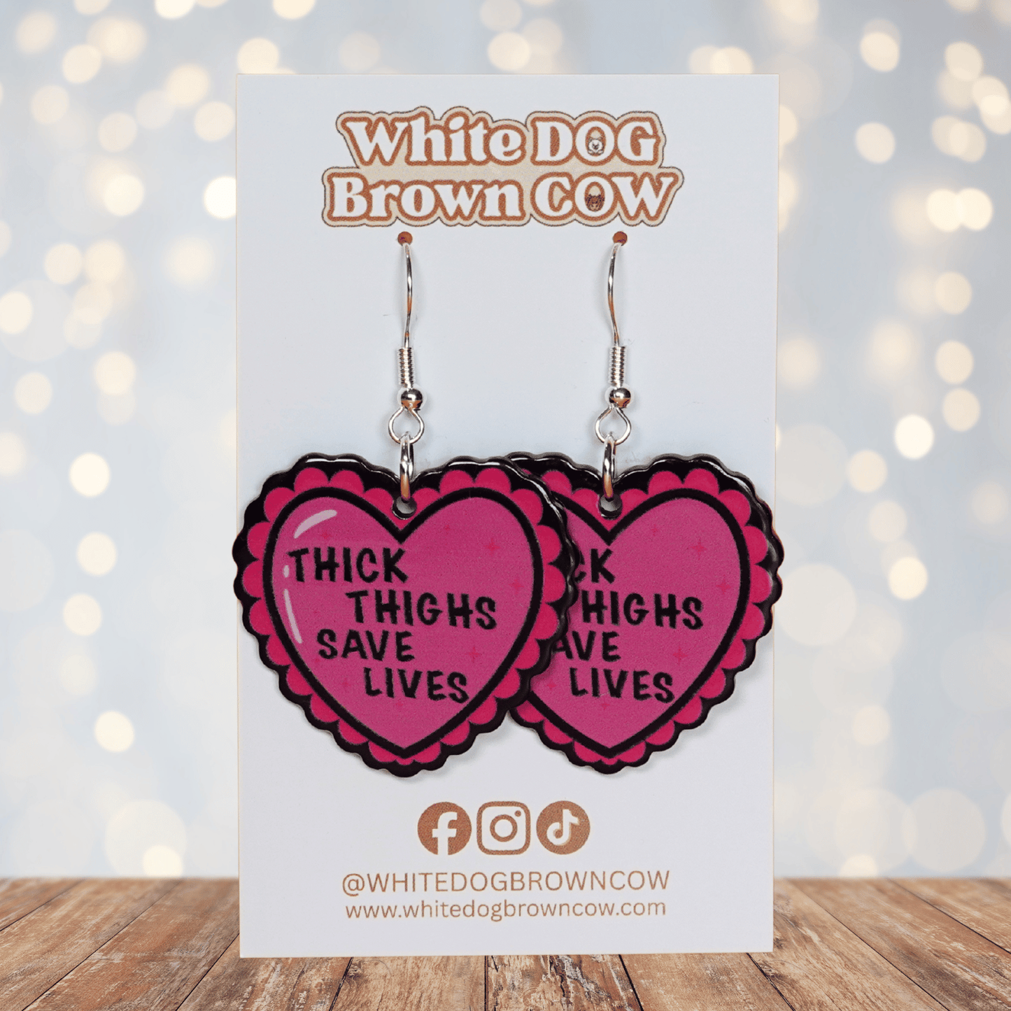Pink heart dangle earrings with text “thick thighs save lives”