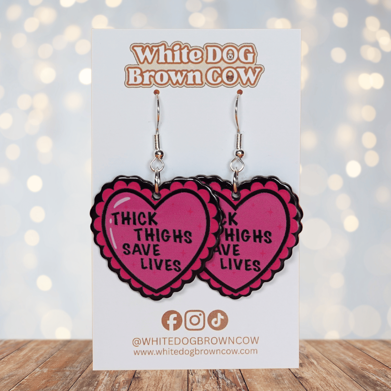 Pink heart dangle earrings with text “thick thighs save lives”