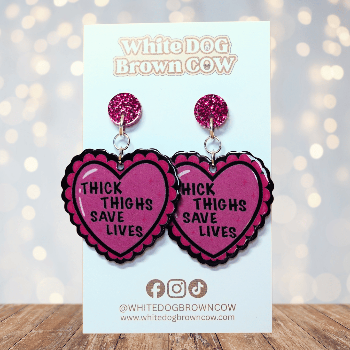 Pink heart dangle earrings with text “thick thighs save lives”