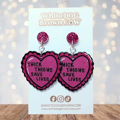 Pink heart dangle earrings with text “thick thighs save lives”