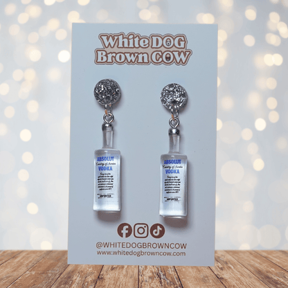 Novelty dangle earrings shaped like clear vodka bottles with a printed vodka-style label design.