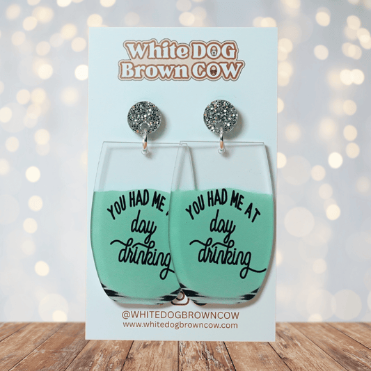 Funny acrylic dangle earrings shaped like wine glasses with mint green drink and text that reads “You had me at day drinking.”