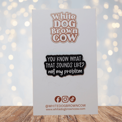 Black and white enamel pin reading “You Know What That Sounds Like? Not My Problem” in bold lettering, funny sarcastic office humor lapel pin.